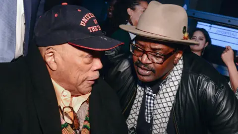 Madison McGaw/BFA.com/Shutterstock Quincy Jones Fab 5 Freddy speaking toge ther in 2019. Jones is wearing a black baseball cap and Freddy has a beige trilby on