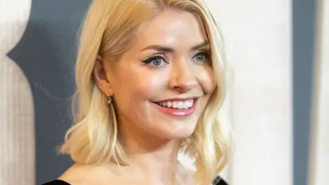 Getty Images Holly Willoughby, with shoulder-length blonde waved hair, smiles off camera