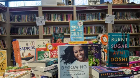 BBC/Kit Taylor A pile of diverse and colourful books in a library.
