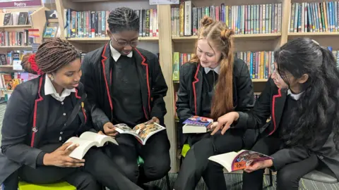 BBC/Kit Taylor Four pupils in a school library sat reading different books together.