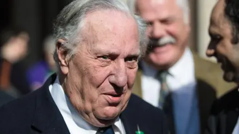 Getty Images Frederick Forsyth is seen in older age in a head and shoulders portrait. He is in a crowd and looking at someone off camera.