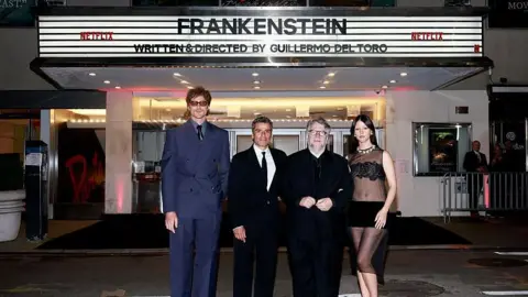 Getty Images Jacob Elordi, Oscar Isaac, Guillermo del Toro and Mia Goth attend Netflix's Frankenstein screening in New York. They are standing outside a cinema with the film's title displayed above the door.