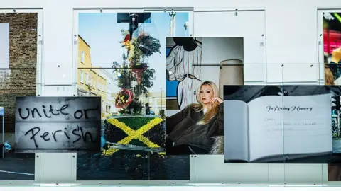 Getty Images A series of Rene Matic's photographs on the gallery wall including a young woman, a floral tribute with a Jamaican flag, graffiti reading "unite or perish" and a book of condolence