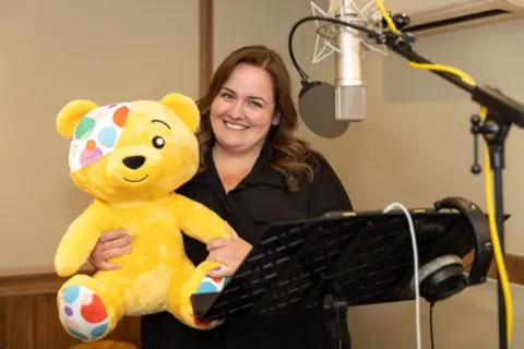 Jessica Gunning with Pudsey Bear in a recording studio.