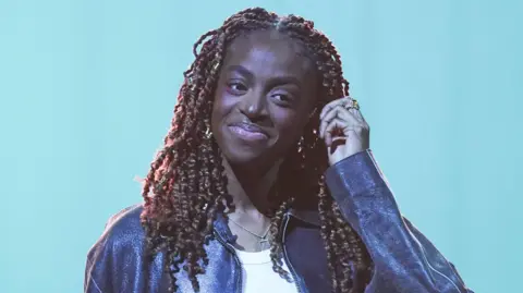 PA Cat Burns pictured smiling and wearing a leather jacket during filming for the Graham Norton Show in December